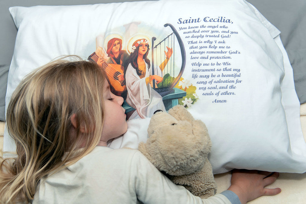 Child sleeping on pillowcase with St. Cecilia picture and prayer.